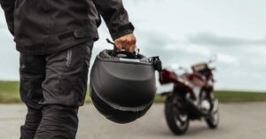 motorcyclist holding helmet walking toward his motorcycle