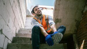 A construction worker holds his sprained ankle after an accident