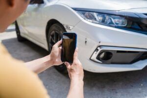 A man takes a photo of his damaged car and wonders what to do after a minor car accident.