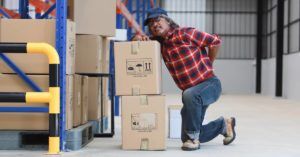 middle-aged warehouse worker grabbing his lower back after an on-the-job injury
