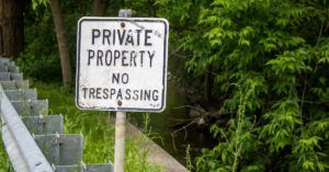 sign reading 'Private Property No Trespassing' behind guardrail