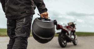 motorcyclist holding helmet walking toward his motorcycle
