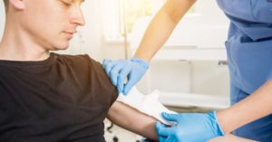 young man receiving medical treatment for a burn on his upper arm