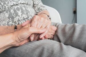 a younger person holding an older person's wrinkled hand