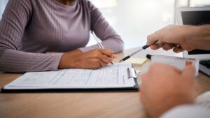 Man Pointing to the Medical Form Woman Filling Out in the Hospital