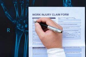 An injured worker with a bandaged hand fills out a claim after seeking legal representation from a Charlotte workplace injury lawyer.