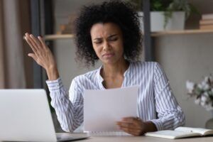 A woman reacts after receiving a notice that an insurance company rejected her claim. If you believe an insurance company acted in bad faith, a lawyer can help you seek damages.