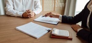 An insurance agent explains to a client why their insurance rate will go up for a claim involving an accident that was not their fault. A bad faith insurance lawyer can challenge an unfair or illegal rate increase.