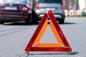 A warning triangle blocks off an accident scene involving an Uber vehicle and another car. If you have been in an Uber crash, a lawyer can determine if you can hold Uber responsible.