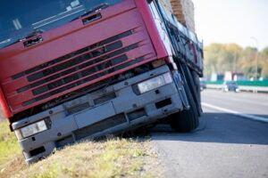 A truck trailer sits in a ditch off an interstate road after the driver lost control of the vehicle. Make sure you are safe and receive medical help before speaking to a lawyer about your options for recovering damages.
