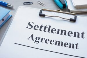 A clipboard that reads “settlement agreement” after a settlement was reached