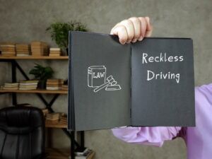 A man holding up a book that talks about reckless driving. An attorney can explain what’s considered reckless driving in North Carolina.