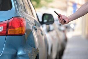A person photographs vehicle damage after a hit-and-run crash. You can get a lawyer for a hit-and-run to pursue damages for your injuries and losses.