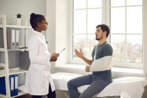 A man in a sling talking to a doctor. Learn about what the most common truck accident injuries are.